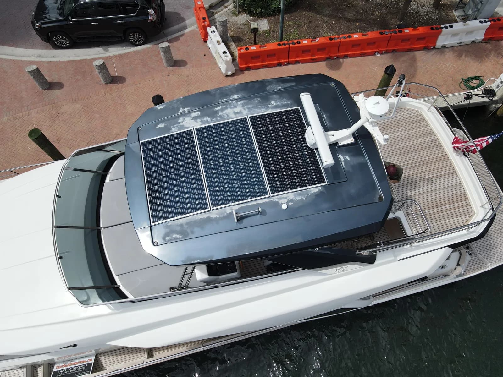 Yacht hardtop seen from above, its gelcoat blotched and chalked grey across the whole horizontal surface around a three-panel solar array.