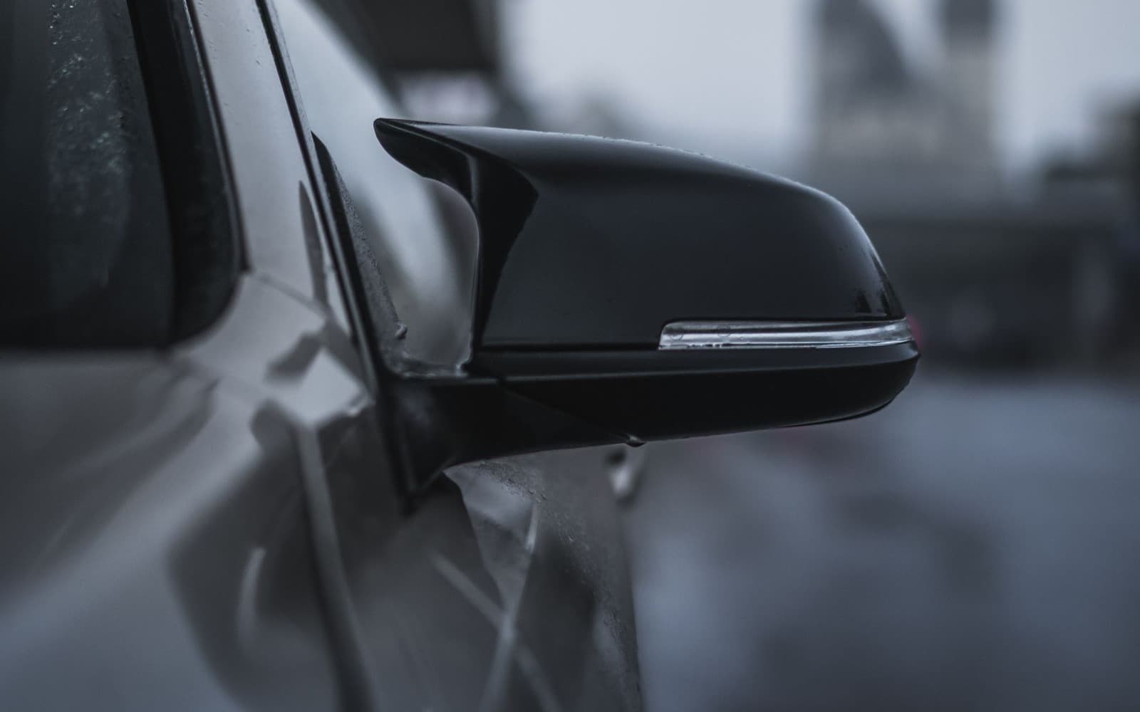 Gloss black mirror cap and black window trim on a white car — crisp blacked-out trim edges