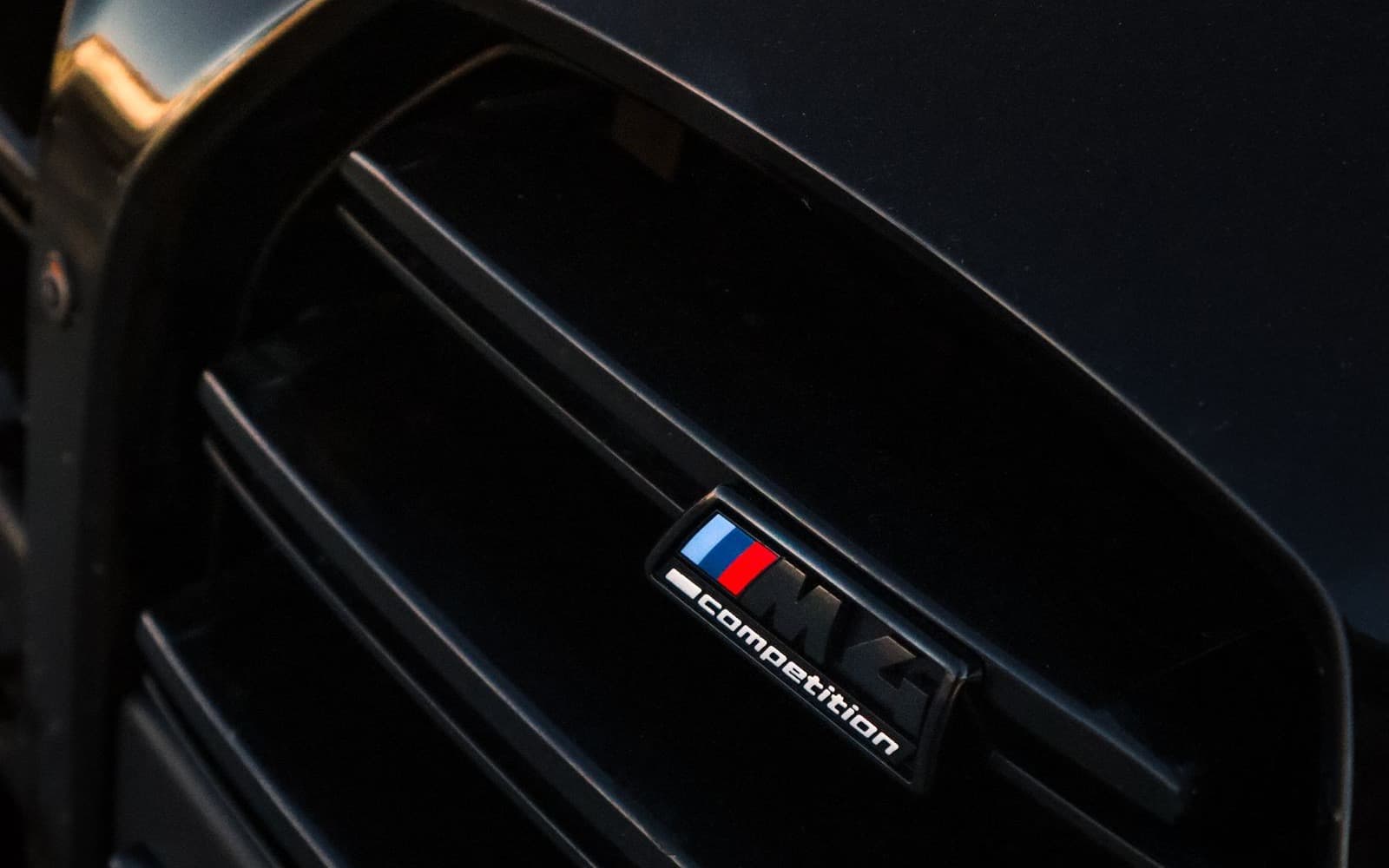 Close-up of a blacked-out BMW grille with gloss black slats and black M badge — full chrome delete