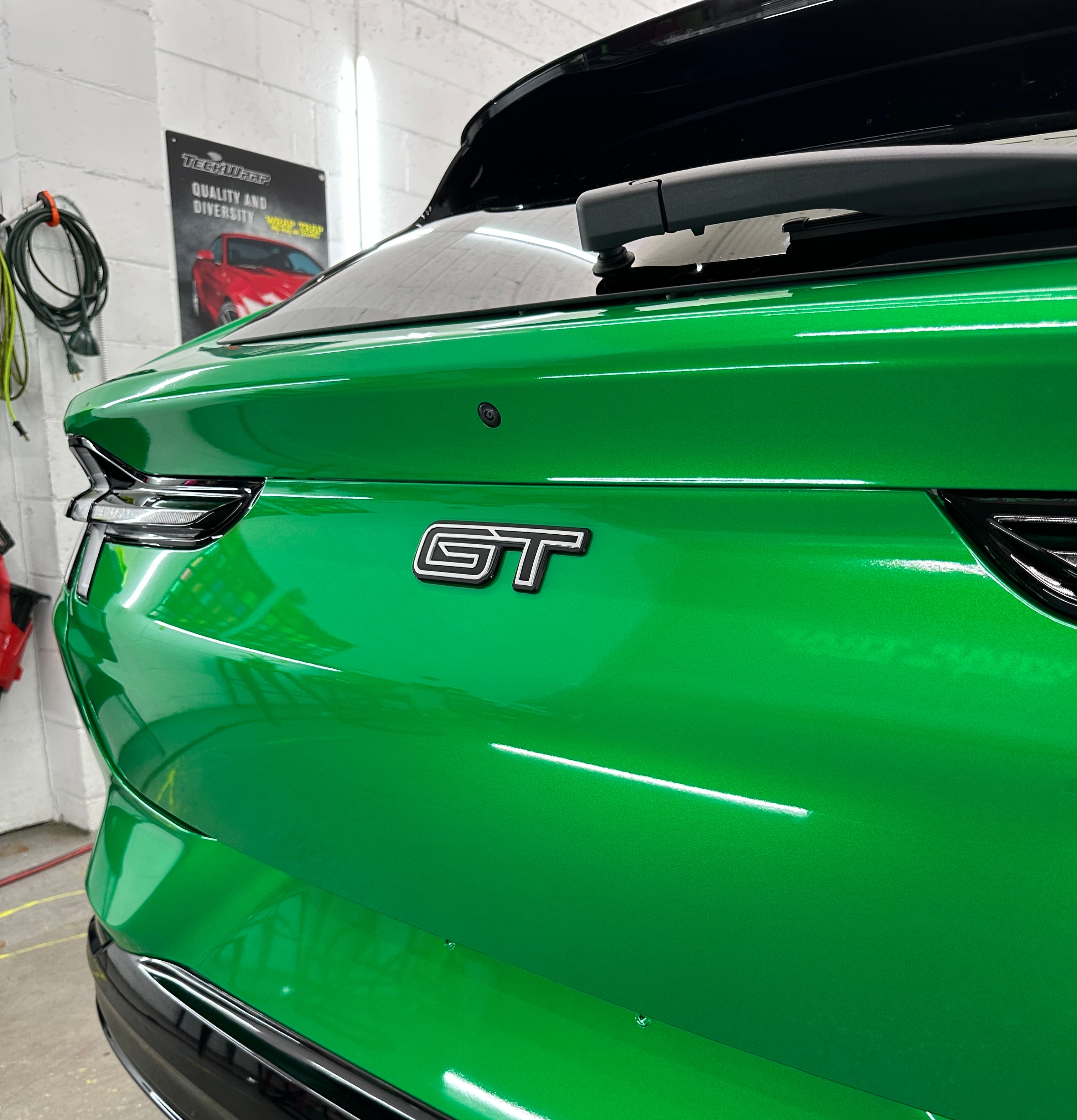 Showroom-gloss green rear end of a Mustang Mach-E GT at the Wrap Trap shop in Hollywood, FL