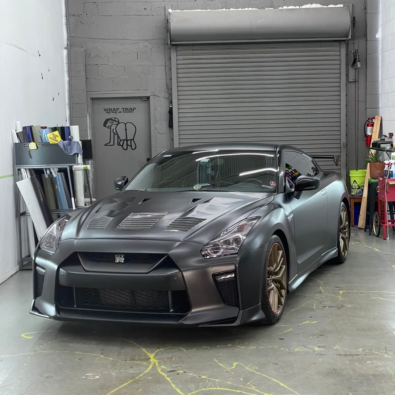 Nissan GT-R in satin dark gray vinyl wrap parked inside the Wrap Trap shop in Hollywood FL