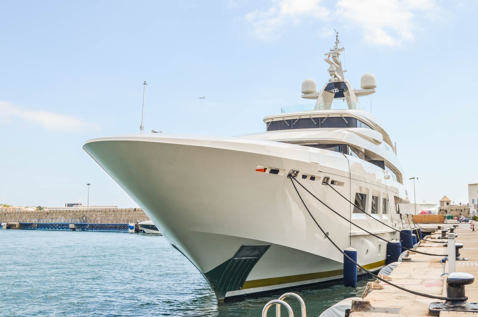 Gleaming white motor yacht hull moored at a marina dock on a sunny day